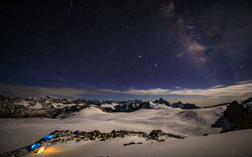 Scenic view of snowcapped mountains against star field at night