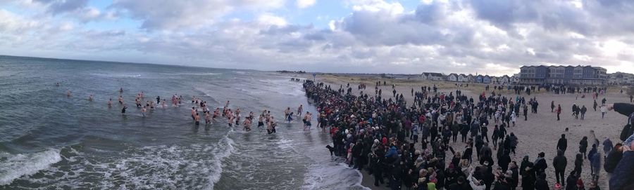 Panoramic view of people in sea against sky