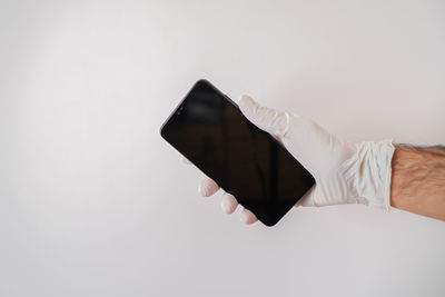 Close-up of hand holding umbrella over white background