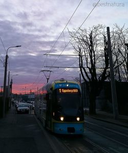 Cars on street in city against sky at dusk