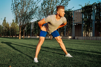 Portrait of young man exercising on field