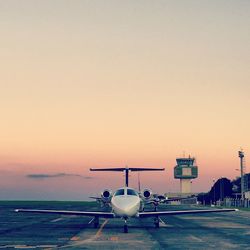 Airplane on runway against sky during sunset