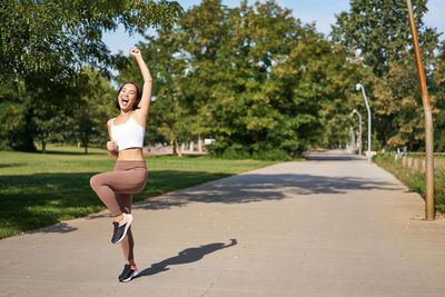Full length of young woman exercising on road