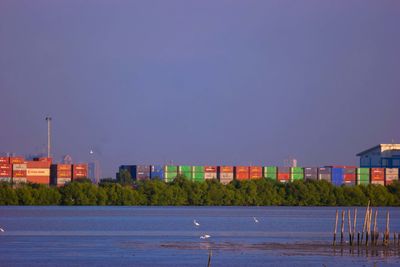 Buildings by sea against clear blue sky