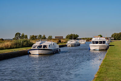 Boats moored in river against clear sky