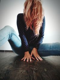 Woman hair on face sitting on hardwood floor against wall