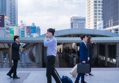 People walking on elevated walkway against buildings in city