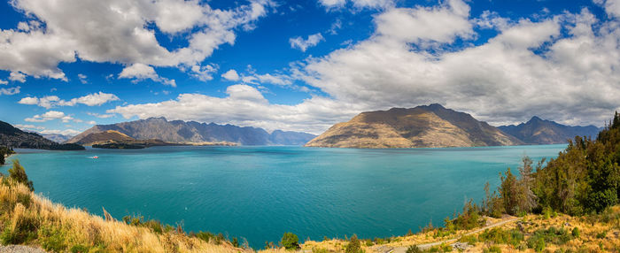 Panoramic view of sea and mountains against blue sky