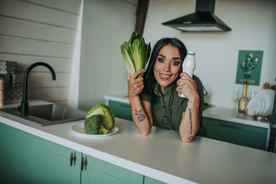 Portrait of smiling woman holding vegetable at home