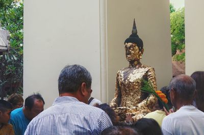 Rear view of people statue outside temple against building