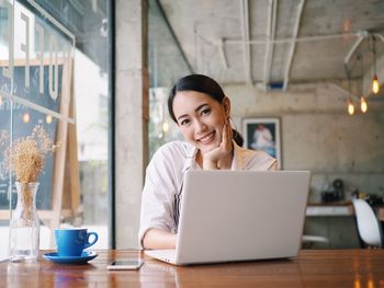 Portrait of young woman using laptop on table