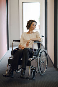 Disabled business woman sitting in wheelchair, with laptop on knees