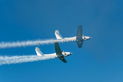 Low angle view of airplane flying against clear blue sky
