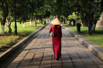 Rear view full length of woman walking on footpath at park