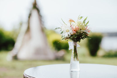 Rustic bouquet of different flowers in a vase on the wigwam background, preparing for the event