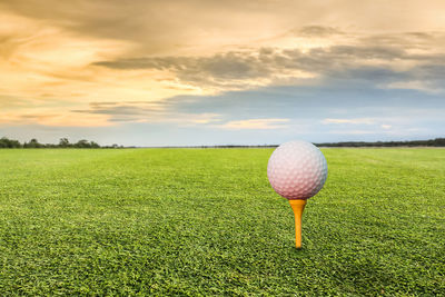 Ball on field against sky during sunset