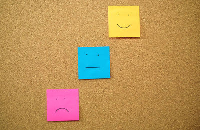 Colorful papers with anthropomorphic faces stuck on wall