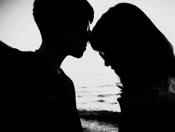 Close-up of silhouette couple standing at beach