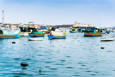 Boats moored in sea against clear blue sky