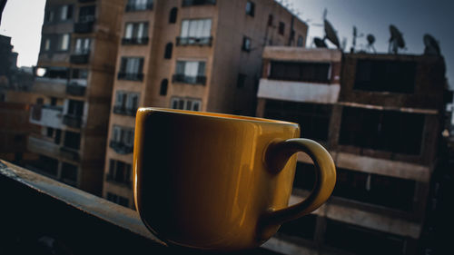 Close-up of coffee cup on table against building