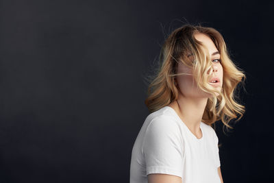 Portrait of beautiful young woman against black background