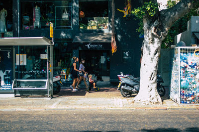 People sitting on street against buildings in city