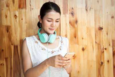 Young woman looking away while standing on wood