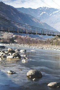 Bridge over river against mountains during winter