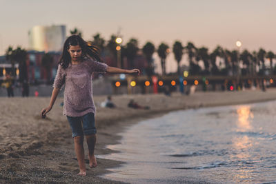 Woman standing at beach during sunset