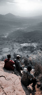 Rear view of people sitting on rock