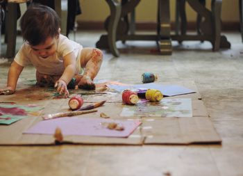Boy playing with watercolor paints while sitting on floor