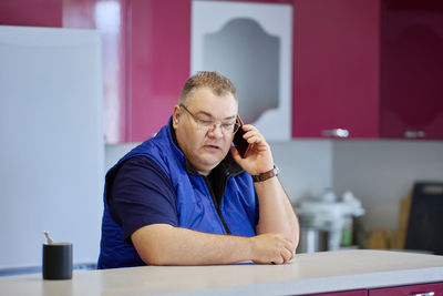Young man using phone while sitting on table