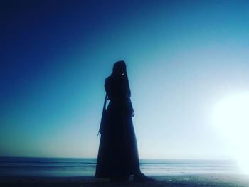 Man standing on beach against clear sky