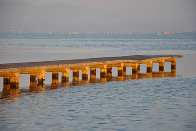 Wooden posts in sea against sky