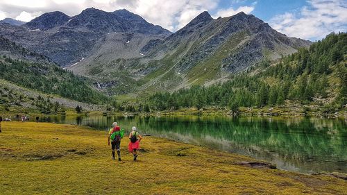 Rear view of people on lake against mountain range