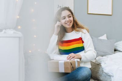 Beautiful happy teenager girl with gift box on bed in cozy children room