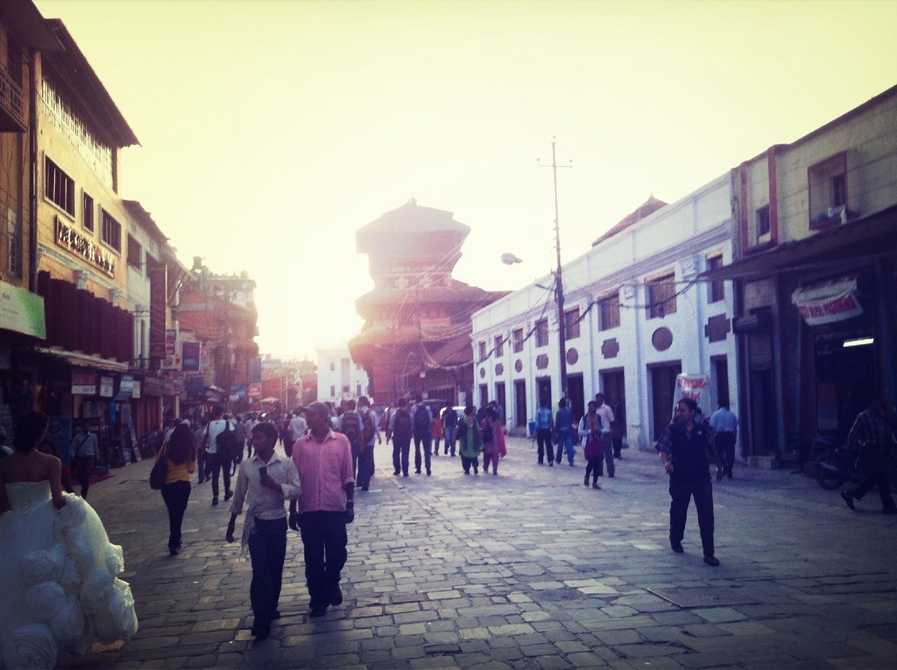 building exterior, architecture, built structure, large group of people, street, city, men, walking, person, city life, lifestyles, city street, the way forward, sunlight, building, mixed age range, clear sky, road, sun