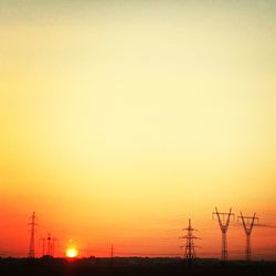 Silhouette of electricity pylon at sunset