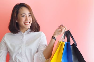 Portrait of smiling young woman standing against multi colored store