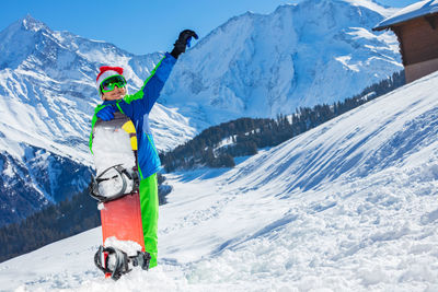 Rear view of woman standing on snowcapped mountain