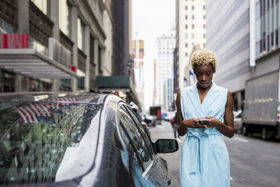 Usa, new york, young blonde african-american woman using smartphone