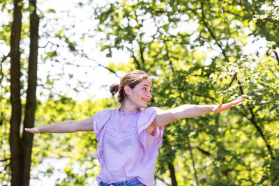 Portrait of young woman standing against trees