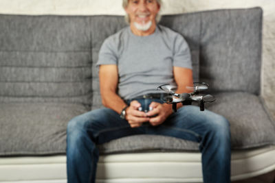 Man holding camera while sitting on sofa