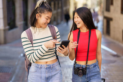 Side view of friends using mobile phone