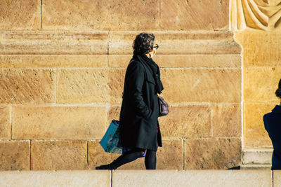 Side view of man and woman walking against wall