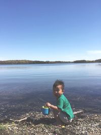 Portrait of boy at lake against sky