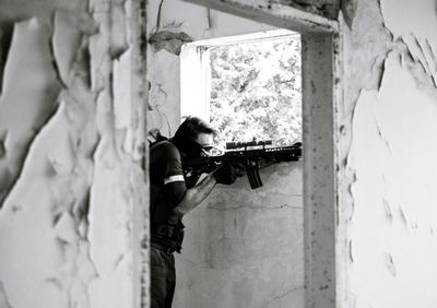 Side view of military man aiming from abandoned building
