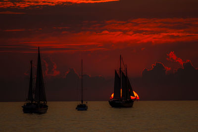 Sailboats sailing on sea against sky during sunset