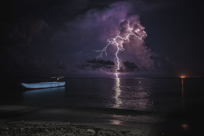 Firework display over sea against sky at night