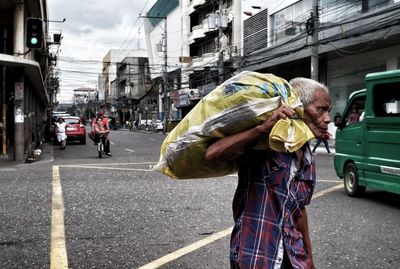 Senior man carrying sack while walking on street